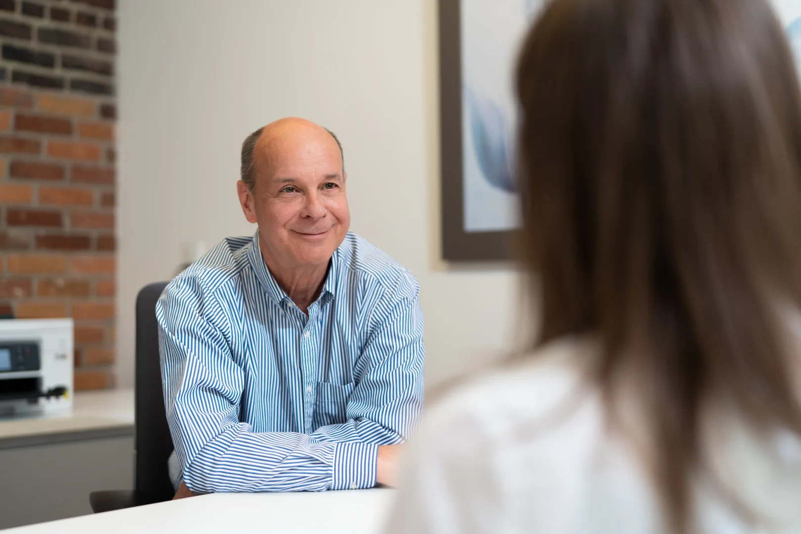 A PeriPharm partner smiling during a discussion with a client across a meeting table